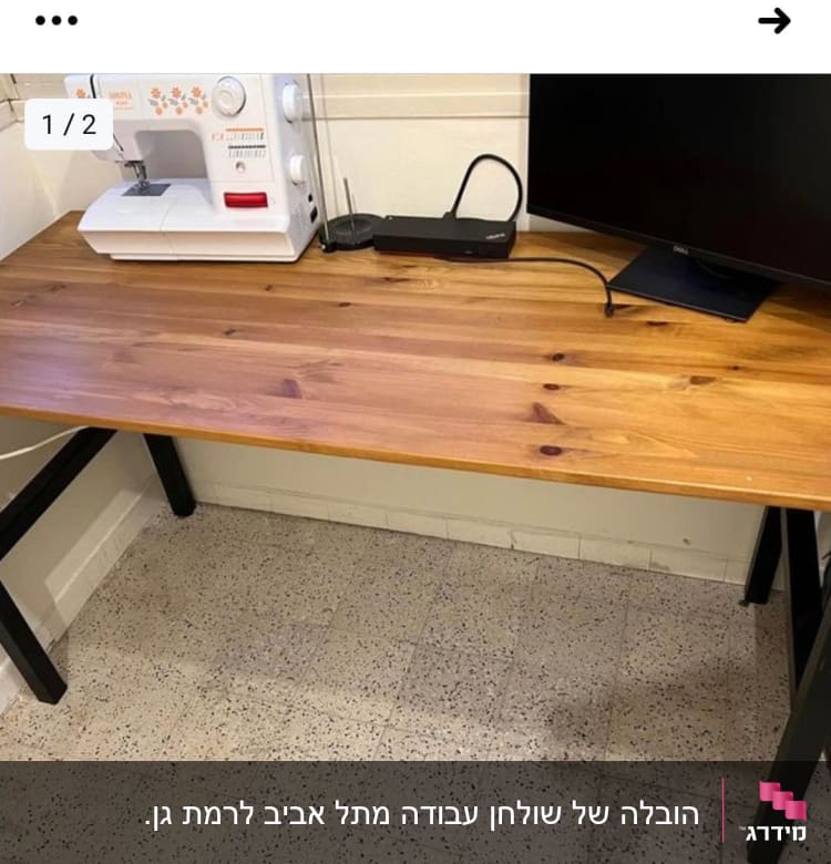 מכונת תפירה על שולחן עץ ליד מסך מחשב